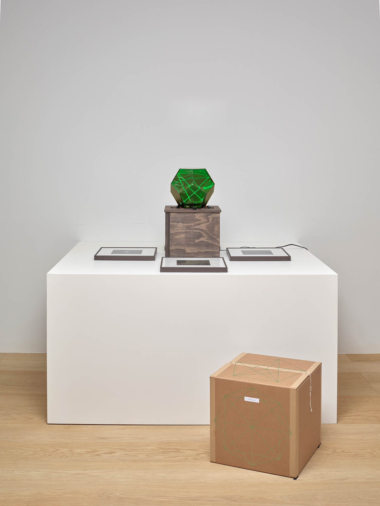 Wonhwa Kim, *Ray Tracing in Dodecahedron*, 2026, Glass geometric vessel, green laser optical installation, plywood panel, pigment print, Vessel 23.3 × 24.5 × 21.5 cm, Display stand 28.5 × 28.5 × 26.2 cm, Full size 28.5 × 28.5 × 47.7 cm. / *Ray Tracing in Stellated Cube, Ray Tracing in Large Dodecahedron, Ray Tracing in Diamond, Ray Tracing in Dodecahedron*, 2026, Pigment print, 15 × 15 cm each.